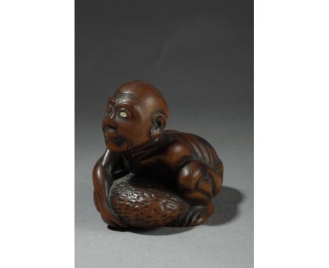 A 19th century Japanese netsuke. Attributed to Gyokuso. In carved wood portraying a kneeling "Amma", the blind masseur, tryin