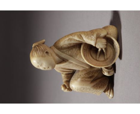 A 19th century Japanese netsuke from Edo period. In carved ivory portraying a man sat on the floor while holding a basket wit