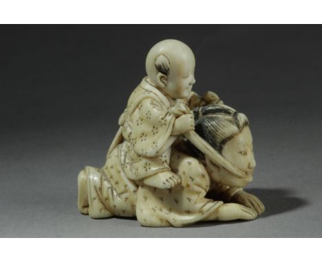 A mid 19th century Japanese netsuke from Edo period. In carved ivory depicting a child playing with her crawling mother. The 