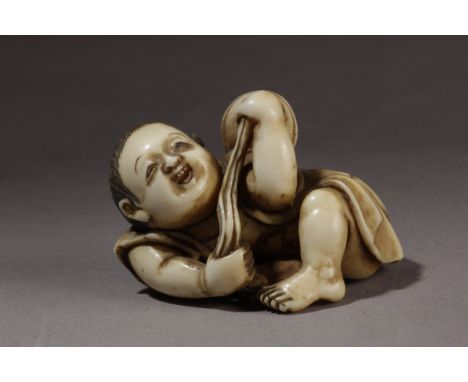 A mid 19th century Japanese netsuke from Edo period. Signed on the base. In carved elephant ivory portraying a child lying on