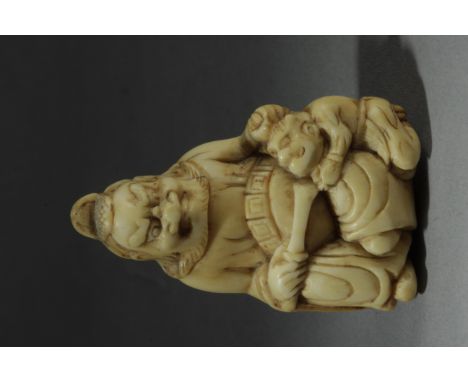 An early 18th century Japanese netsuke from Edo period. In carved elephant ivory depicting a seated Shoki who is grabbing by 