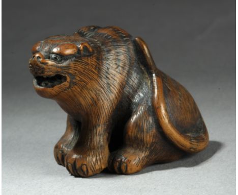 A 19th century Japanese netsuke from Meiji period. In carved wood portraying a tiger with horn eyes, 3 cm. high.