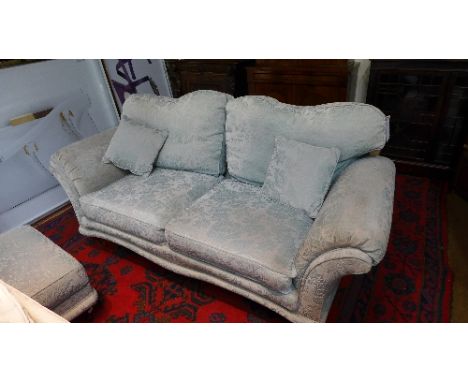 A three seater sofa upholstered in turquoise floral fabric raised on castors