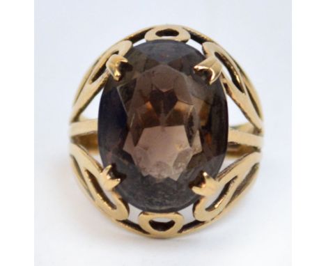 A 9ct gold smoky quartz ring, the oval quartz within a scrolling pierced frame and four claw setting, size K.