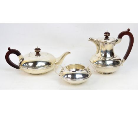 A George V hallmarked silver three piece tea service of squat form, the twin handled sucrier with stylised cast acanthus hand