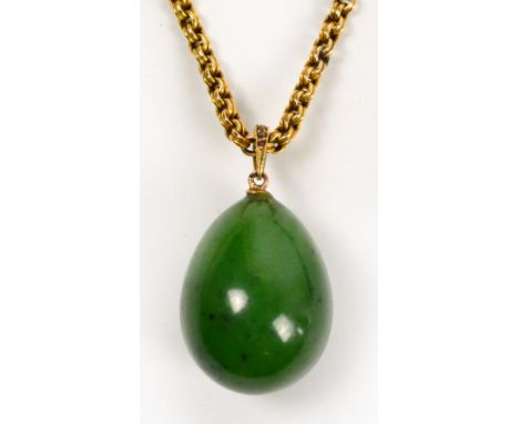 A yellow metal chain supporting a nephrite jade egg shaped pendant, length of chain approx 53cm.