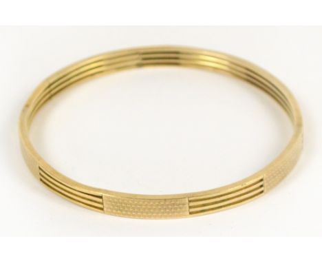 A 9ct yellow gold bangle with a pierced and engine turned panel decoration, diameter 7.5cm, approx 20.2g. CONDITION REPORT: M