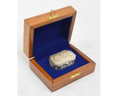 A filigree decorated white metal snuff box of rectangular form with canted corners, presented in a hinged walnut outer box, u