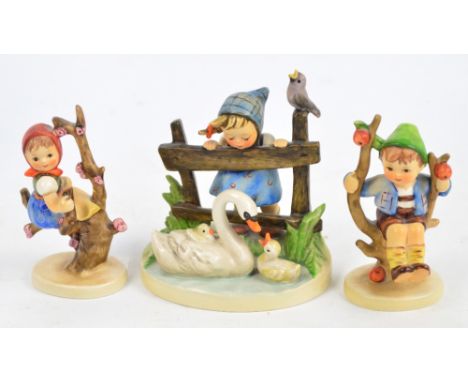 Three Goebel Hummel figures; boy on apple tree, girl on prunus branch, and girl watching swans. CONDITION REPORT: Crazing, ot