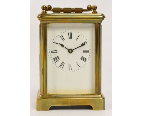 A c.1900 French brass carriage clock with swing loop handle above white enamel dial set with Roman numerals on a bracket foot