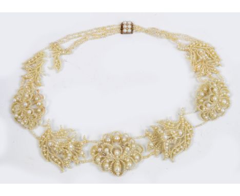 A cased Edwardian fancy natural pearl necklace set with seven clusters of pearls each on a mother of pearl platform with 9ct 