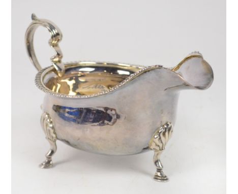 A George V hallmarked silver sauce boat raised on three stepped hoof feet with shell caps and with gadrooned rim, Adie Brothe