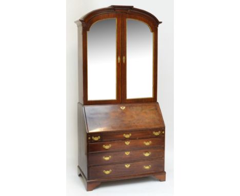 An 18th century red walnut bureau bookcase, the upper section with twin bevelled mirrored doors enclosing adjustable shelves 