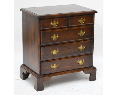 A reproduction oak chest of small proportions, the moulded rectangular top above two short and three long drawers raised on b