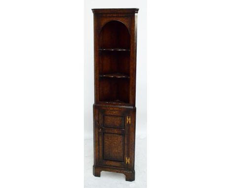 A reproduction Titchmarsh & Goodwin oak free standing corner cupboard of narrow proportions, the upper section with open arch