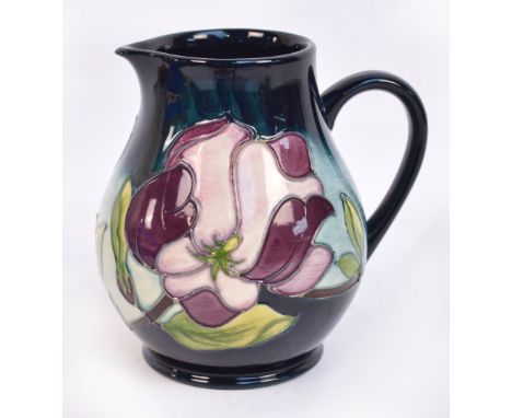 A modern Moorcroft jug in purple "Magnolia" pattern on a dark blue fading to pale blue ground, green mark impressed to base, 