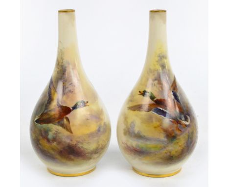 A pair of Royal Worcester bottle vases, each hand painted with a duck in flight with landscape beyond and both signed "Jas St