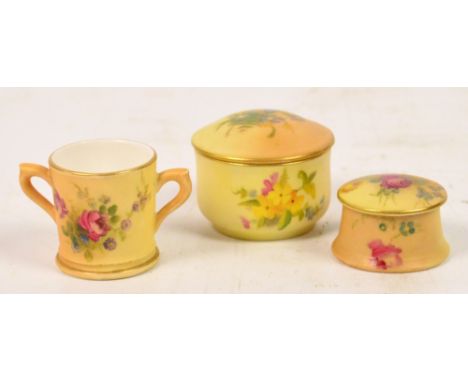 Three pieces of miniature Royal Worcester blush ivory; two circular small pots and covers and a twin handled loving cup, each