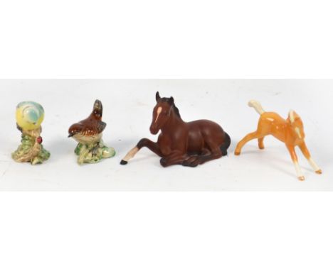 Four Beswick models; a large matt brown lying foal, a small prancing Palomino foal, a wren and a blue tit. CONDITION REPORT: 