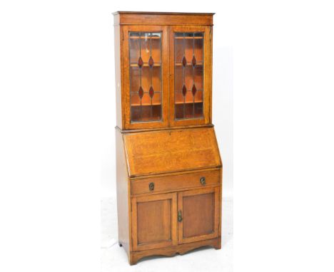 An Edwardian oak bureau bookcase, the moulded cornice above pair of leaded glazed doors enclosing two shelves above fall fron