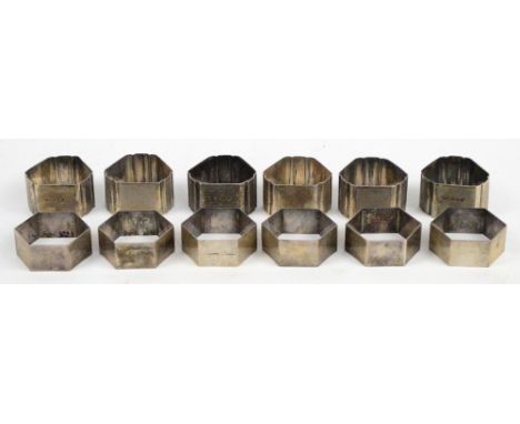 A set of six George VI hallmarked silver napkin rings with engine turned decoration, London 1947, and a set of six white meta