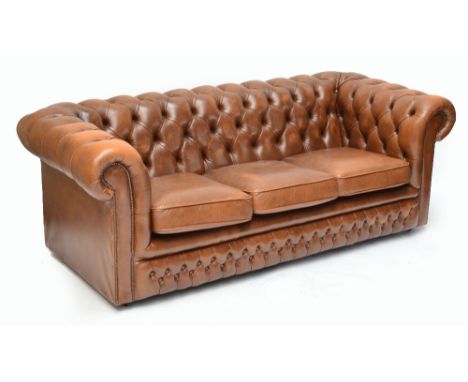 A brown leather upholstered three seater Chesterfield settee. CONDITION REPORT: Discolouration to cushions. No excessive wear