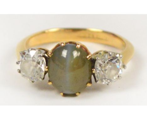 An 18ct yellow gold dress ring with central chrysoberyl cat's eye cabochon stone flanked by two diamonds of 0.25ct, set in pl