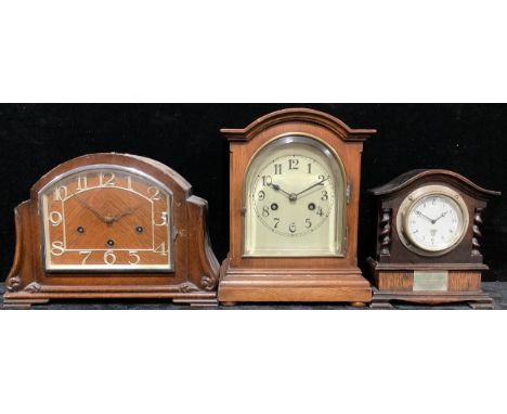 An Edwardian oak mantel clock, arched case, glazed bevelled door, the dial with Arabic numerals, twin winding holes, stepped 