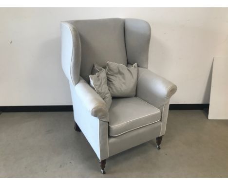 A first half 20th century wing back armchair, in grey upholstery, AF 