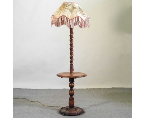 An early 20th century carved oak standard lamp, with a spirally turned column and shade, 175cm high