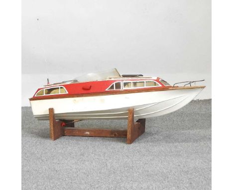 A red and white painted remote control model boat, on stand, 84cm long