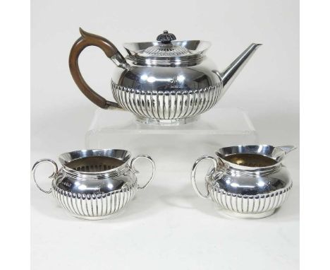 A Victorian silver three piece tea service, of compressed shape, with half gadrooned decoration, London 1882, engraved with a