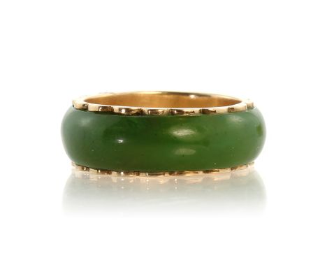 A jade eternity ring in 14ct yellow gold designed as a polished jade band with gold mount. Ring size N / 6.5. Weight 3.8g.