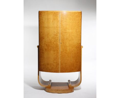 An Epstein burr walnut veneer cocktail cabinet, on scroll legs, the twin curved doors opening to mirrored compartment with sl