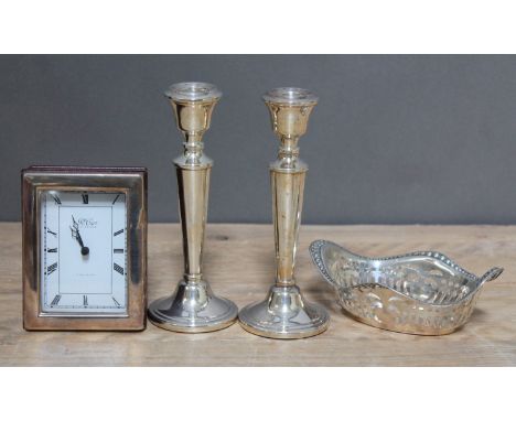 A mixed lot of hallmarked silver comprising a pair of candlesticks, a pierced bon bon dish and a silver framed clock, various