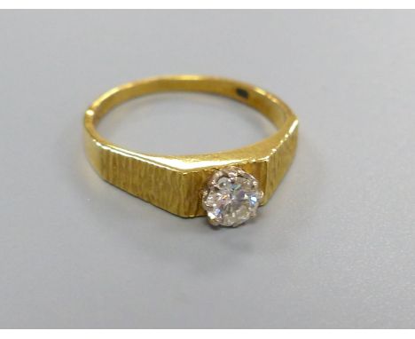 A modern 18ct gold and solitaire diamond ring, with textured shoulders, size N, gross 2.9 grams, the stone weighing approxima