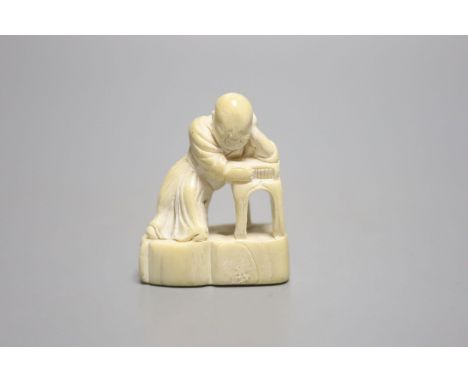 A Japanese ivory netsuke of a sleeping scholar at his table, 18th/19th century, height 4.5cm