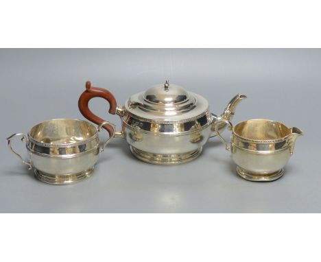 A matched silver three-piece tea service of squat reeded circular form, comprising teapot, milk jug and two-handled sugar bow