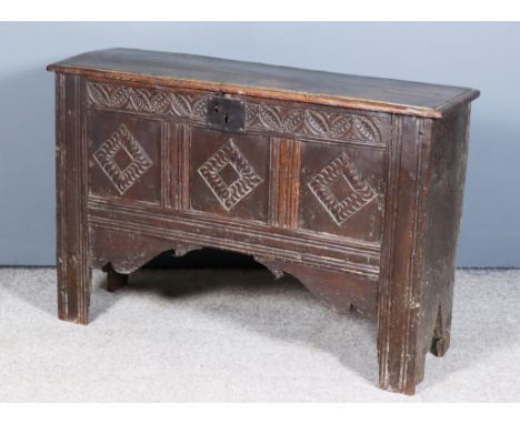A 17th Century Oak Plank Coffer with Three Panel Front, the lid with moulded edge, the frieze carved with leaf ornament above