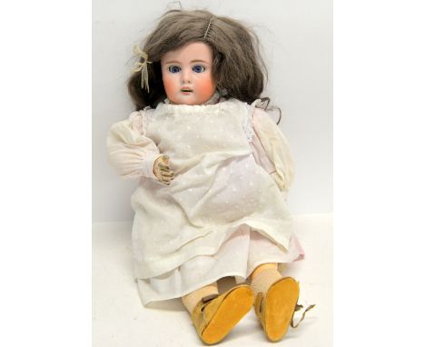 Early 20th century bisque headed doll with jointed composition body in pink and white striped dress and with brunette hair an