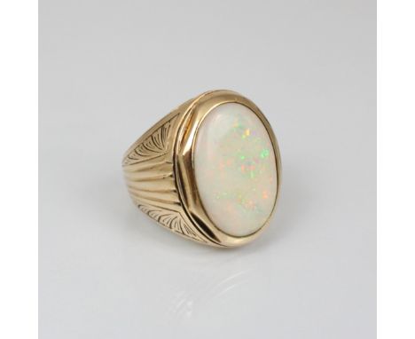 An opal cocktail ring, possibly American, the oval opal cabochon within yellow metal mount leading to engraved shoulders and 