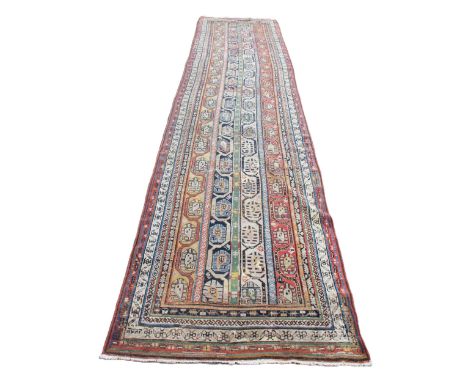 A Turkish wool runner, multi coloured, the central field with four rows of linked geometric guls, within multiple borders, 46