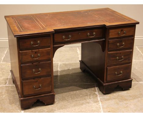 An Edwardian mahogany kneehole desk, of inverted breakfront form, the desk top inset with a skiver over a central recessed fr
