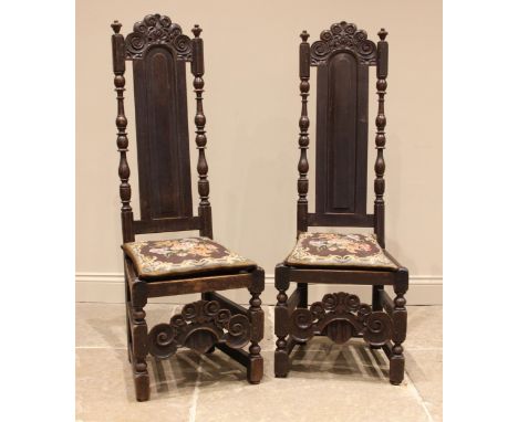 A pair of Carolean style oak hall chairs, 19th century, the panel backs with a scroll carved pediment, bobbin and baluster tu