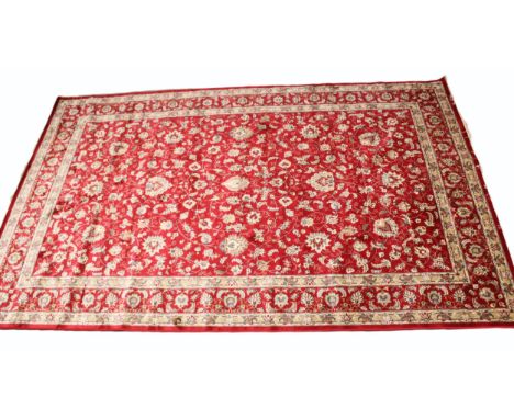 A rich red ground full pile Kashmir carpet with an all over trailing foliate design, enclosed by ivory ground borders, 304cm 