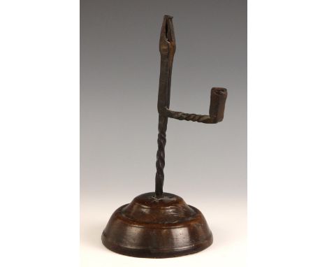 A wrought iron rush light holder, 18th century, of typical form with pivoting jaws and twisted details, set to a turned fruit