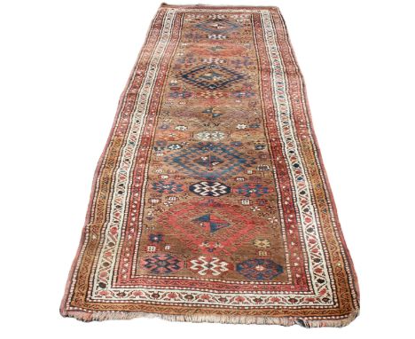 A Caucasian runner, in brown, coral and blue colourways, the central field with five openwork lozenge medallions, punctuated 