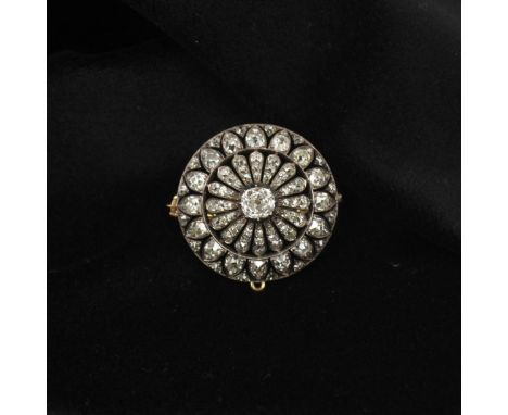 A 19th century diamond brooch, the central old cut diamonds in white metal cut down setting edge, encompassed by surround of 