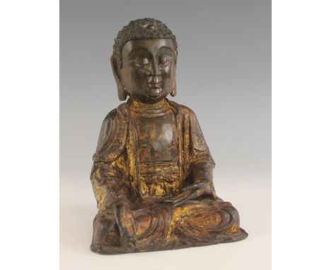 A Chinese bronze and partially gilt lacquered buddha, Ming Dynasty, modelled seated in dhyanasana, the right hand extended in