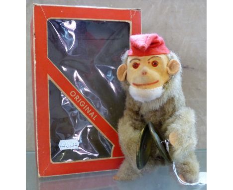 An Original West Germany plush covered figure of a monkey bandsman, seated playing the cymbals, 18cm high, in window box